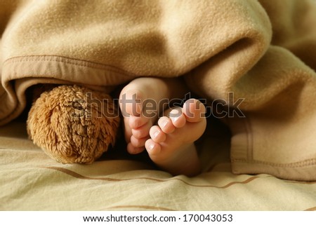 little baby feet under a warm blanket (in beige color)