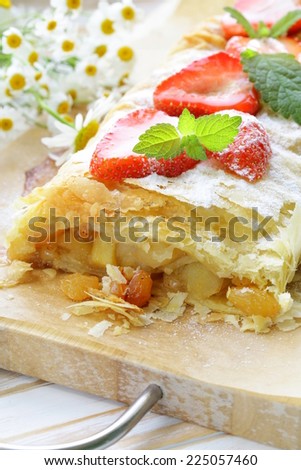 traditional apple strudel with strawberries and powdered sugar