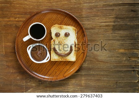 breakfast serving funny face on the plate (toast, chocolate spread and coffee)