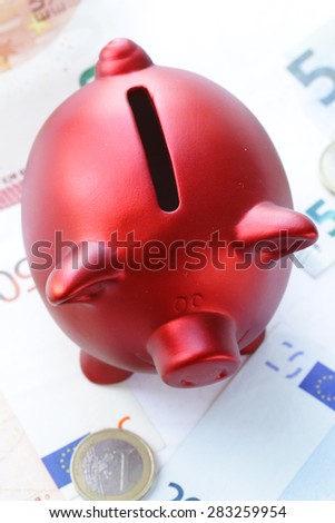 red piggy bank with euro banknotes and coins