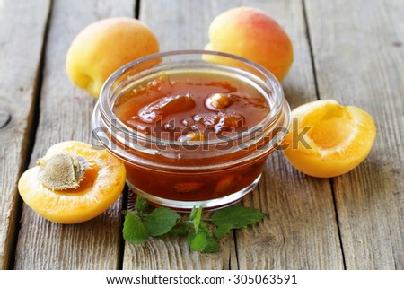 Apricot peach jam in a glass jar on a wooden background