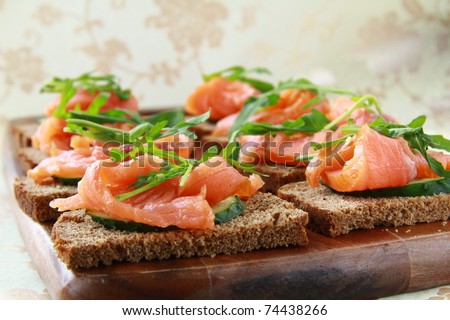 Sandwich with smoked salmon and arugula on a wooden board