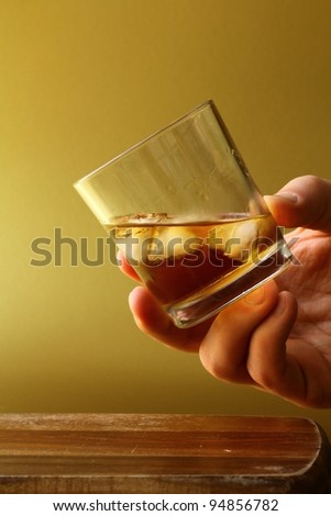 glass of scotch whiskey and ice in hand