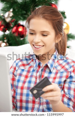 happy woman with laptop computer and credit card over christmas tree....