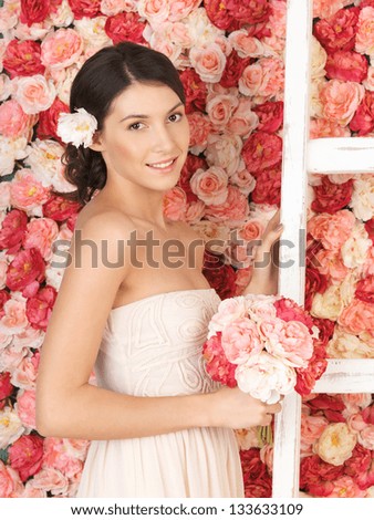 woman with bouquet of flowers and background full of roses