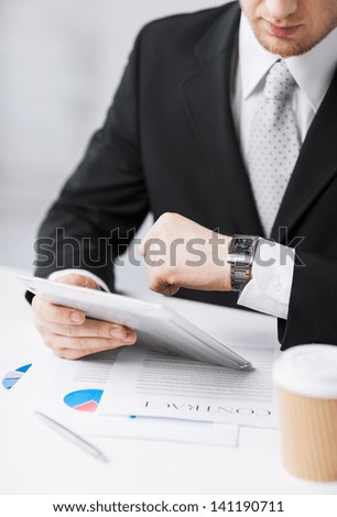 man with tablet pc and cup of coffee looking at watch