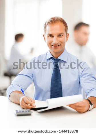 middle-aged businessman with notebook and calculator in office