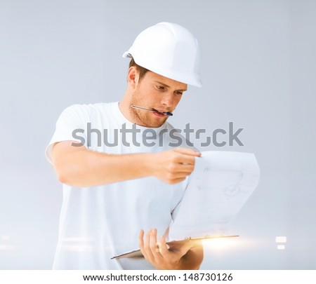 architecture concept -  male architect in helmet looking at blueprint