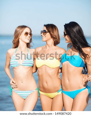 summer holidays and vacation concept - girls in bikinis walking on the beach