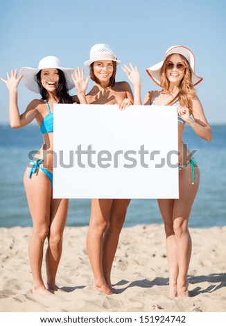summer holidays and vacation - girls in bikinis holding blank white board on the beach