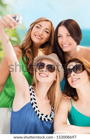 summer holidays and technology - girls taking selfie with digital camera in cafe on the beach