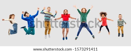 childhood, motion and happiness concept - happy little children jumping in air over grey background