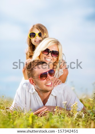 summer holidays, children and people concept - happy family with blue sky and green grass