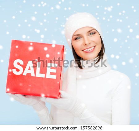 shopping, gifts, christmas, x-mas concept - smiling woman in winter clothes with red sale sign