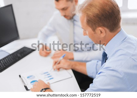 businesss and office concept - businessmen with notebook discussing graphs on meeting