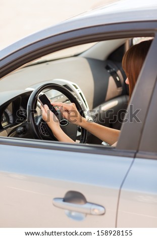 transportation and vehicle concept - woman using phone while driving the car
