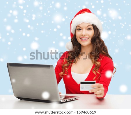 christmas, x-mas, online shopping concept - woman in santa helper hat with laptop computer and credit card