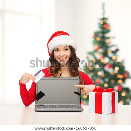christmas, x-mas, online shopping concept - woman in santa helper hat with gift box, laptop computer and credit card
