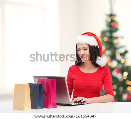 christmas, x-mas, online shopping concept - woman with shopping bags and laptop computer