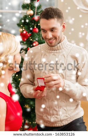love, couple, christmas, x-mas, winter, relationship and dating concept - romantic man proposing to a woman in red dress
