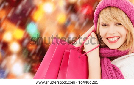 winter, people and happiness concept - woman in pink hat and scarf with many shopping bags