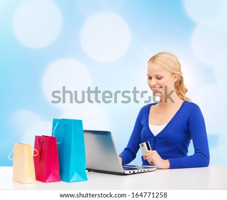christmas, x-mas and online shopping concept - smiling woman with shopping bags, laptop and credit card