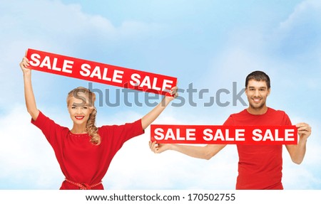 shopping, sale and christmas concept - smiling woman and man with red sale signs