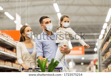 sale, family and pandemic concept - happy mother, father and little daughter wearing face protective medical masks for protection from virus disease with shopping cart buying food at supermarket