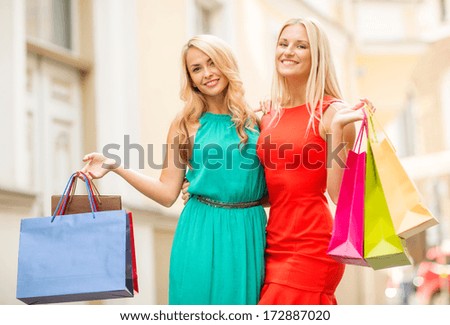 sale, tourism, shopping and happy people concept - two beautiful women with shopping bags in the ctiy