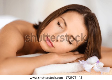 health, beauty, resort and relaxation concept - beautiful woman in spa salon lying on the massage desk