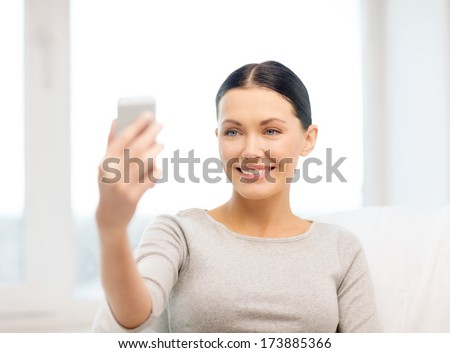 home, technology, photography and internet concept - woman taking picture of herself with smartphone camera