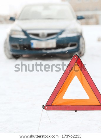 transportation, winter and vehicle concept - closeup of warning triangle and car