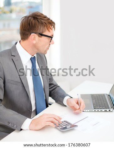 business, office, school and education concept - businessman with laptop computer, papers and calculator