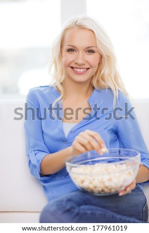 food, happiness and people concept - smiling young girl with popcorn ready to watch movie at home