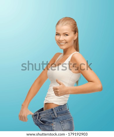 fitness, diet and good shape concept - sporty woman showing big pants and thumbs up