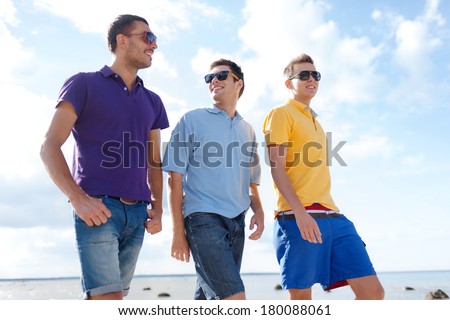 summer, holidays, vacation, happy people concept - group of male friends walking on the beach
