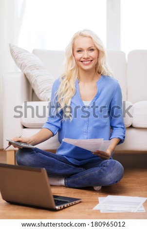 tax, finances, technology, home and happiness concept - smiling young woman with papers, laptop computer and calculator at home