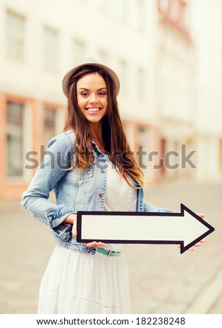 holidays and tourism concept - beautiful girl showing direction with arrow in the city