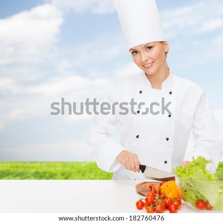 cooking and food concept - smiling female chef chopping vegetables