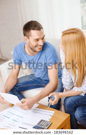 tax, finances, family, home and happiness concept - smiling couple with papers and calculator at home