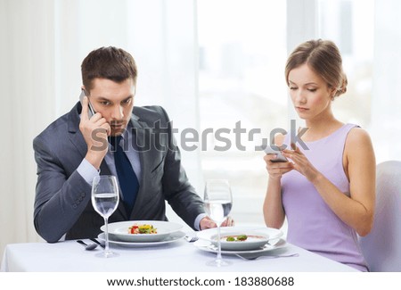 restaurant, couple, technology and holiday concept - busy couple with smartphones at restaurant