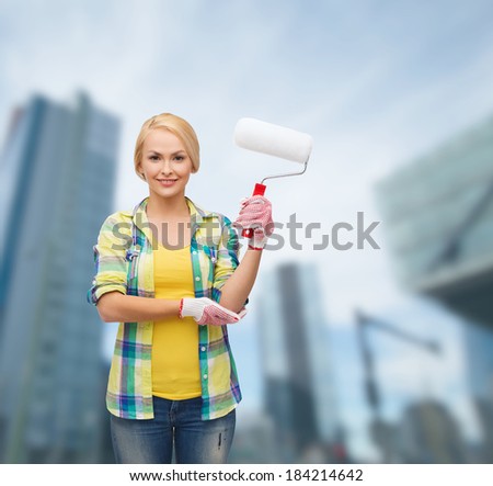 repair, construction and maintenance concept - smiling woman in gloves with paint roller