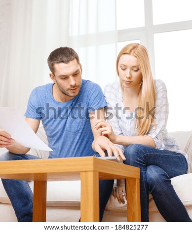 tax, finances, family, home and happiness concept - busy couple with papers and calculator at home