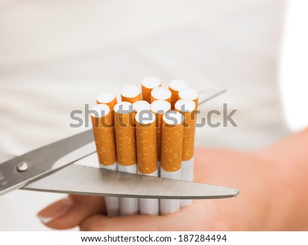 anti-smoking concept - close up of scissors cutting many cigarettes