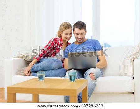 home, technology and relationships concept - smiling couple with laptop computer at home
