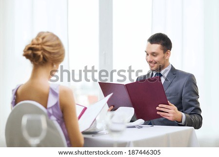 restaurant, couple and holiday concept - smiling young man looking at menu at restaurant
