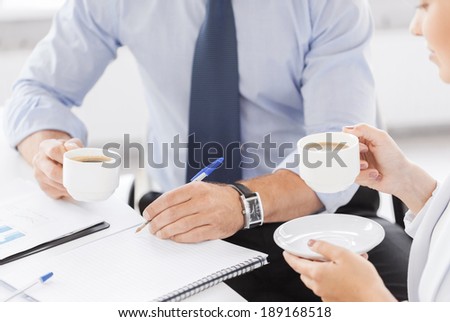 business, school and education concept - smiling businesswoman and businessman discussing something in office