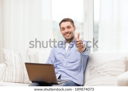 business, technology and e-learning concept - smiling man working with laptop at home