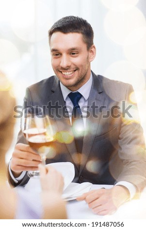 restaurant, couple and holiday concept - smiling young man with glass of red wine looking at girlfriend or wife at restaurant