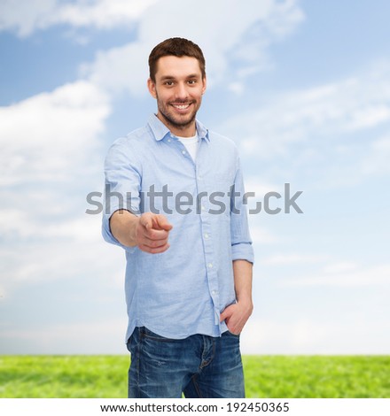 happiness and people concept - smiling man pointing finger at you
